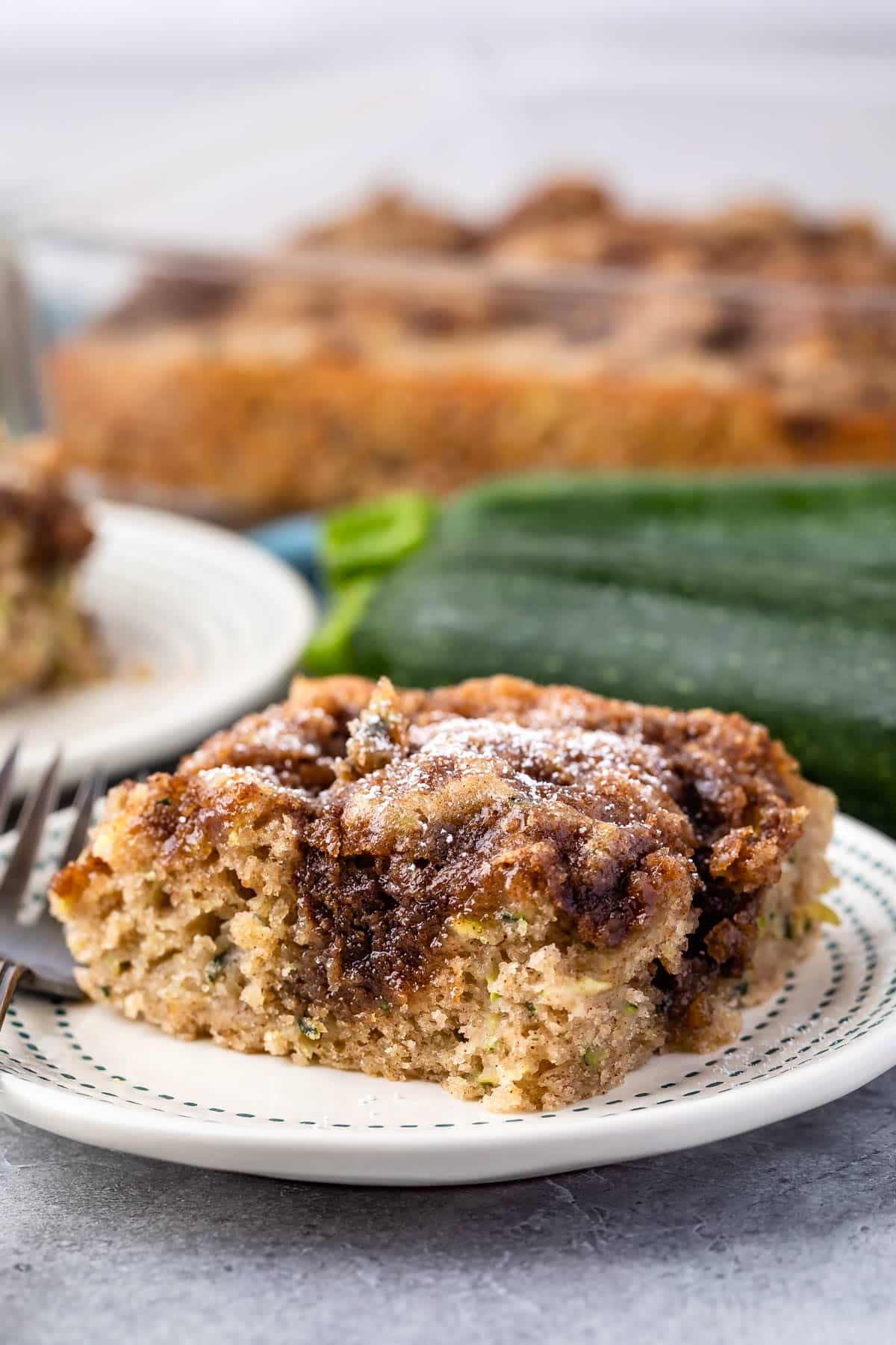 slice of square coffee cake on a white plate with powdered sugar on top.