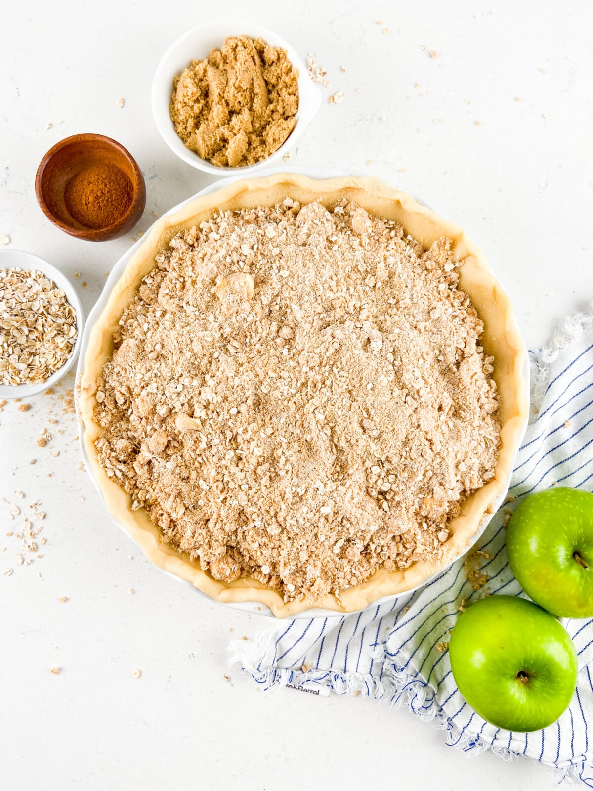 crumble on top of unbaked pie with ingredients around.