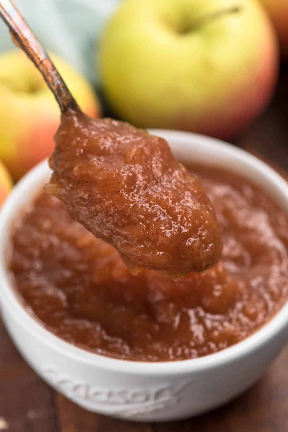 crockpot applesauce in a white bowl on a silver spoon.