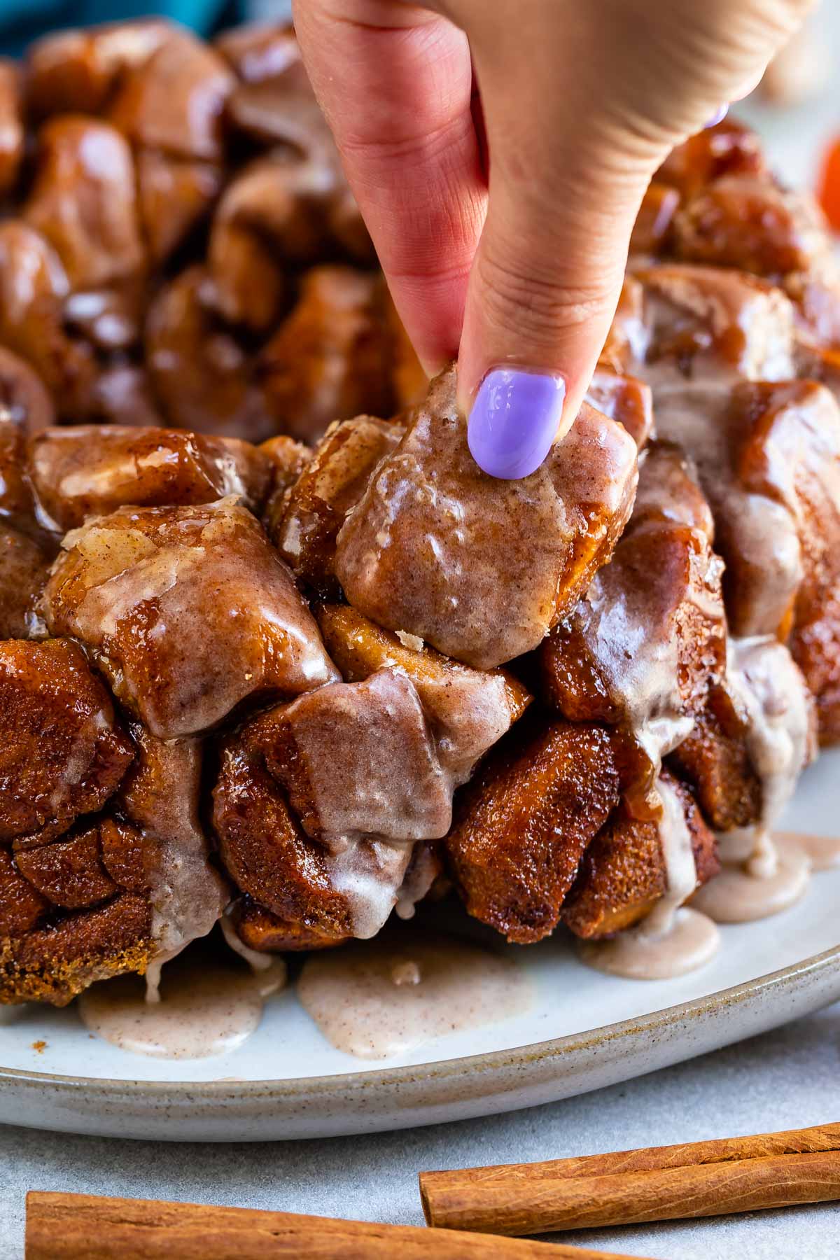 monkey bread on a grey plate with icing dripped over the top.