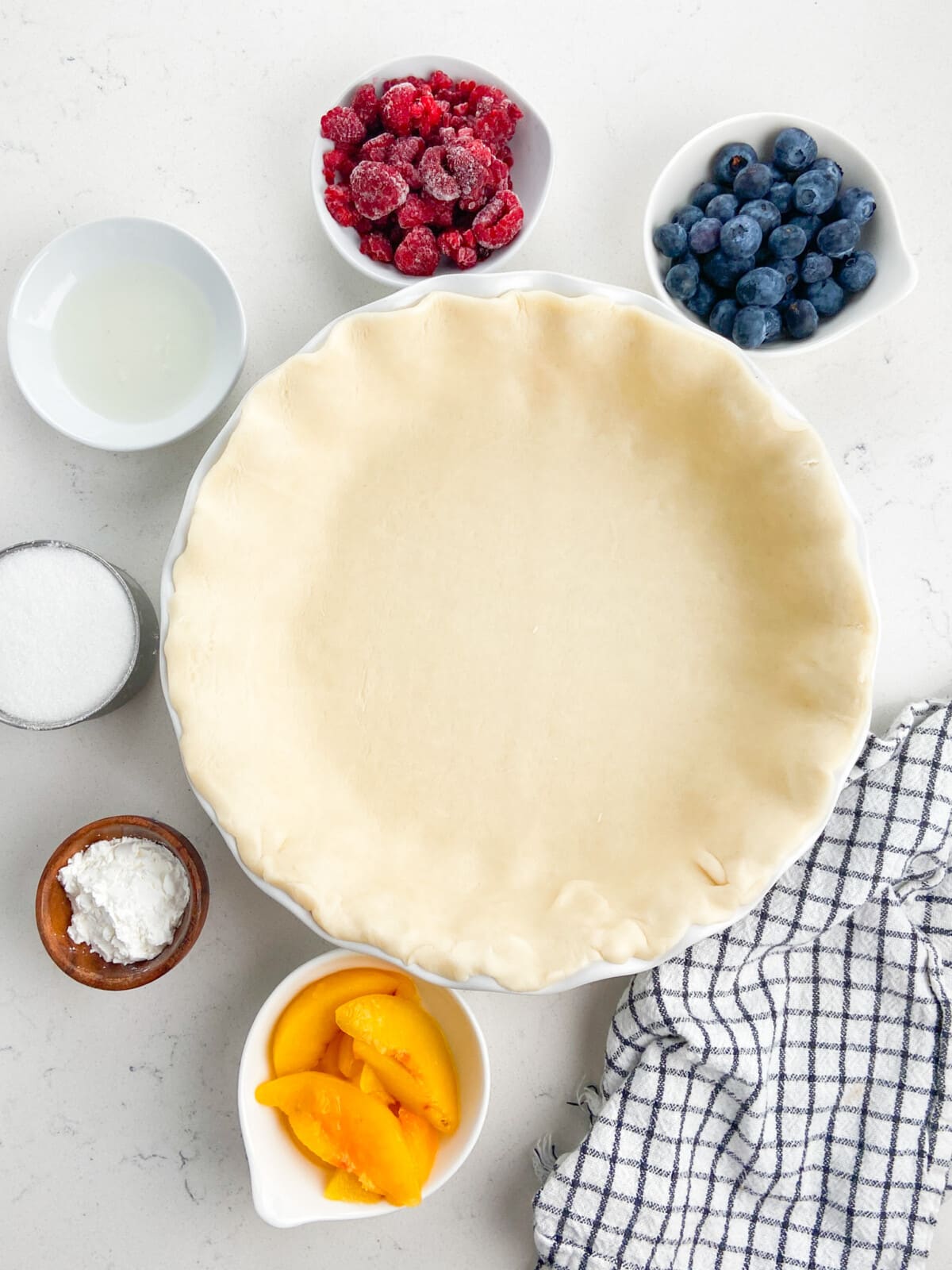 pie crust with bowls of berries and ingredients around