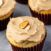 almond cupcake with brown frosting with an almond slice on top.