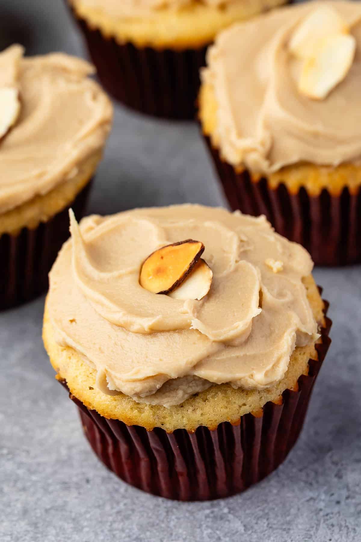 almond cupcake with brown frosting with an almond slice on top.