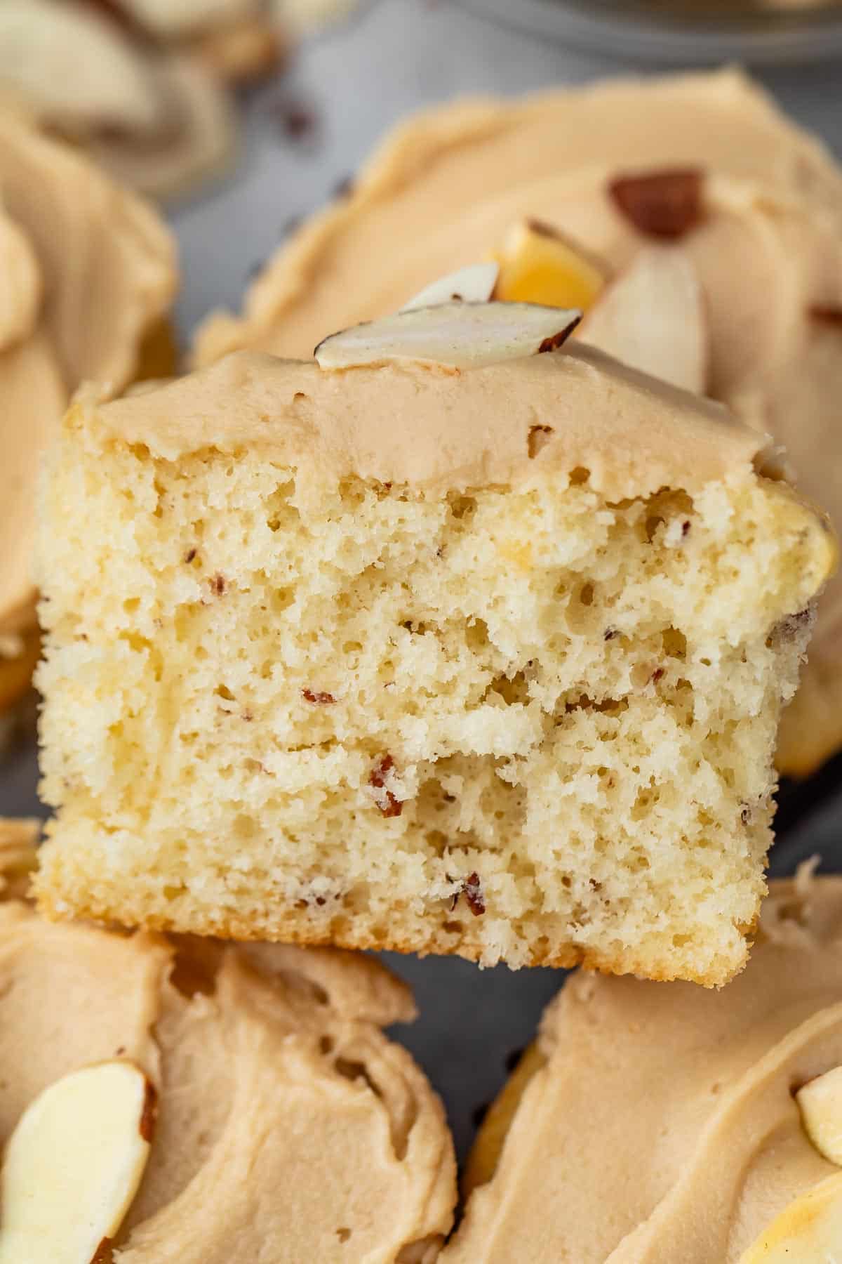 almond cupcake with brown frosting with an almond slice on top.