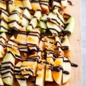 chopped apples on a cutting board with chocolate sauce dripped on top.