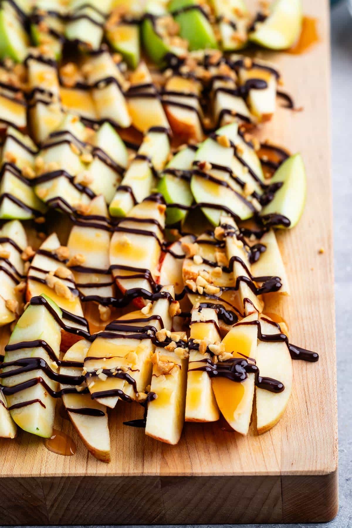 chopped apples on a cutting board with chocolate sauce dripped on top.