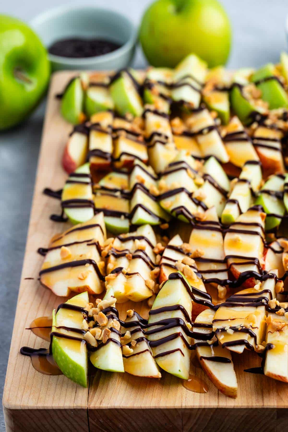 chopped apples on a cutting board with chocolate sauce dripped on top.
