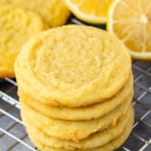 stacked lemon cookies with sliced lemons in the background.