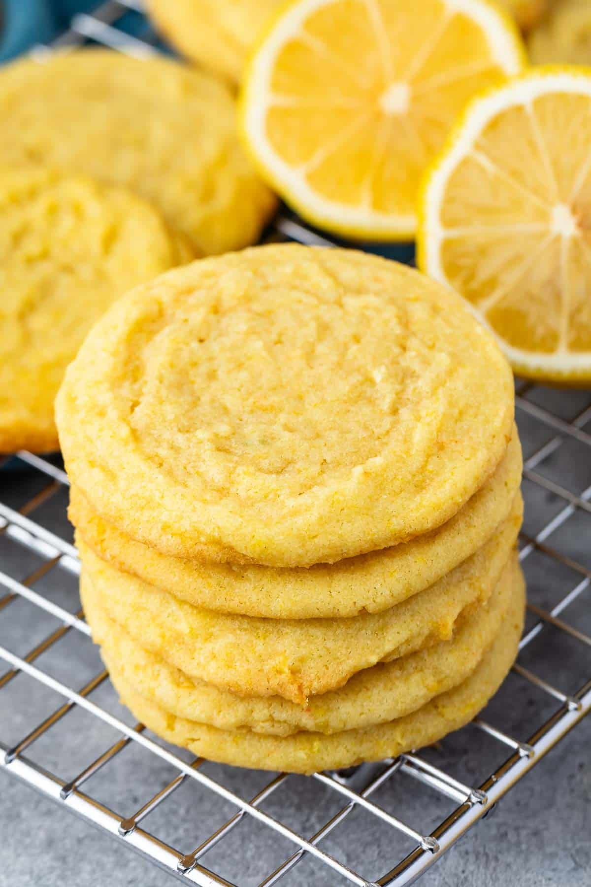 stacked lemon cookies with sliced lemons in the background.