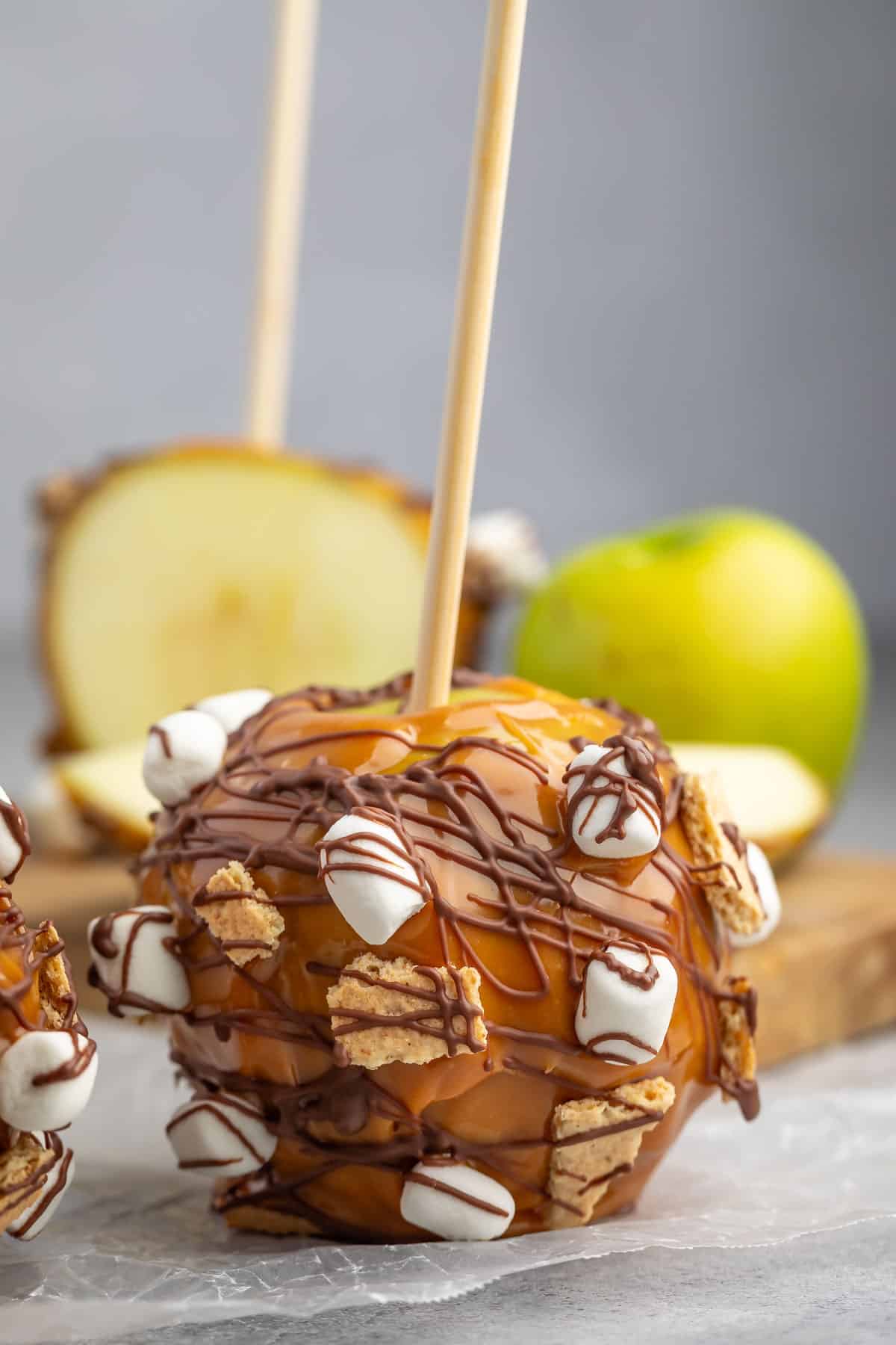 green apple dipped in caramel and chocolate with marshmallows and graham cracker stuck to side.