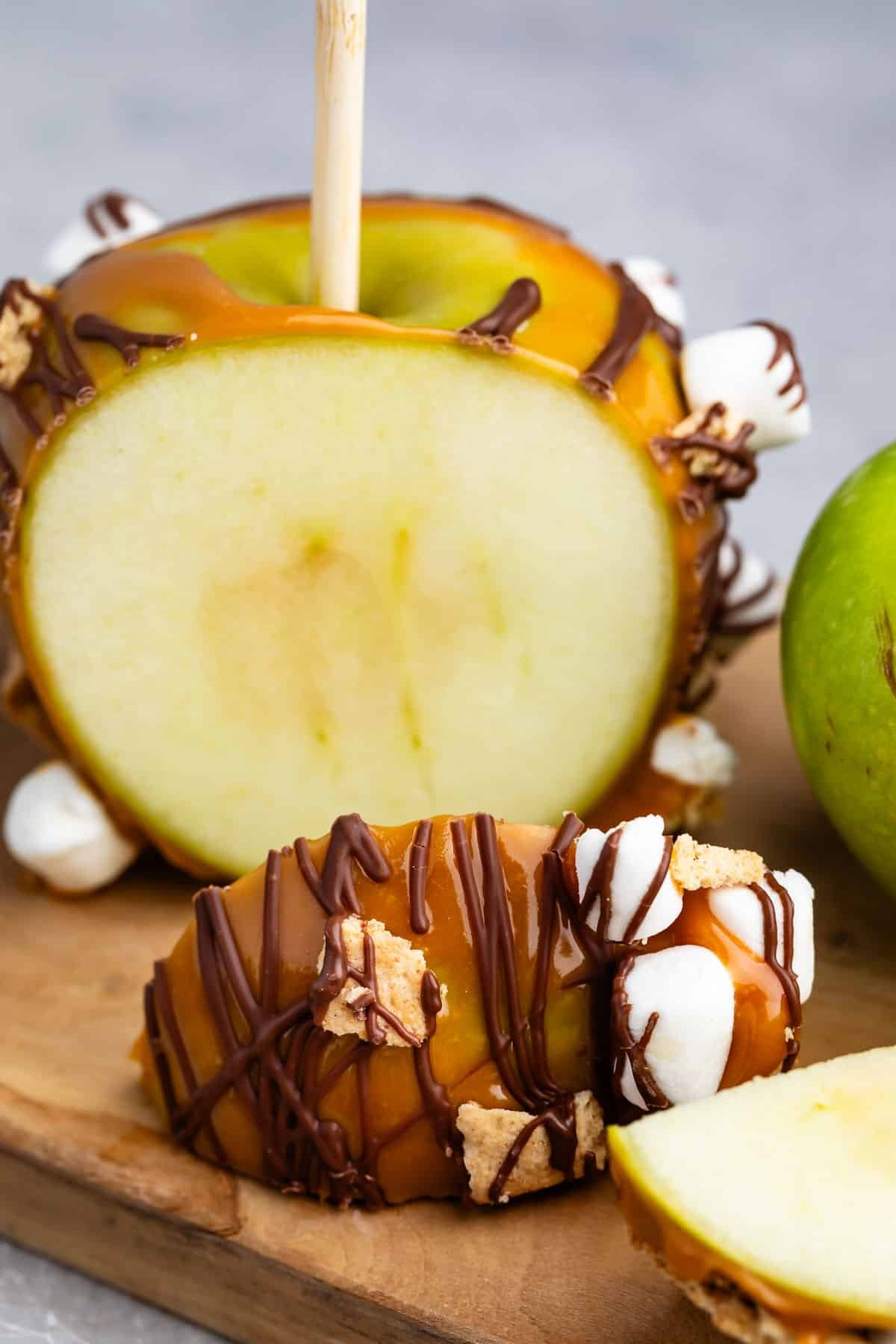 green apple dipped in caramel and chocolate with marshmallows and graham cracker stuck to side.