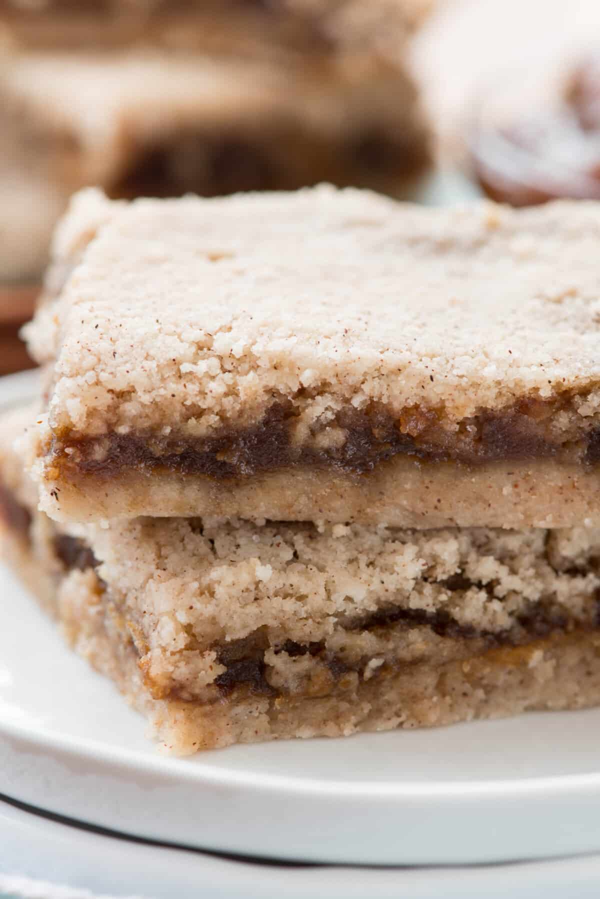 brown layered bars stacked on a white plate.