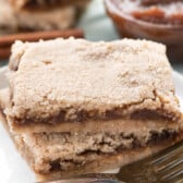 brown layered bars stacked on a white plate.