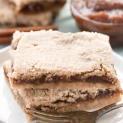 brown layered bars stacked on a white plate.