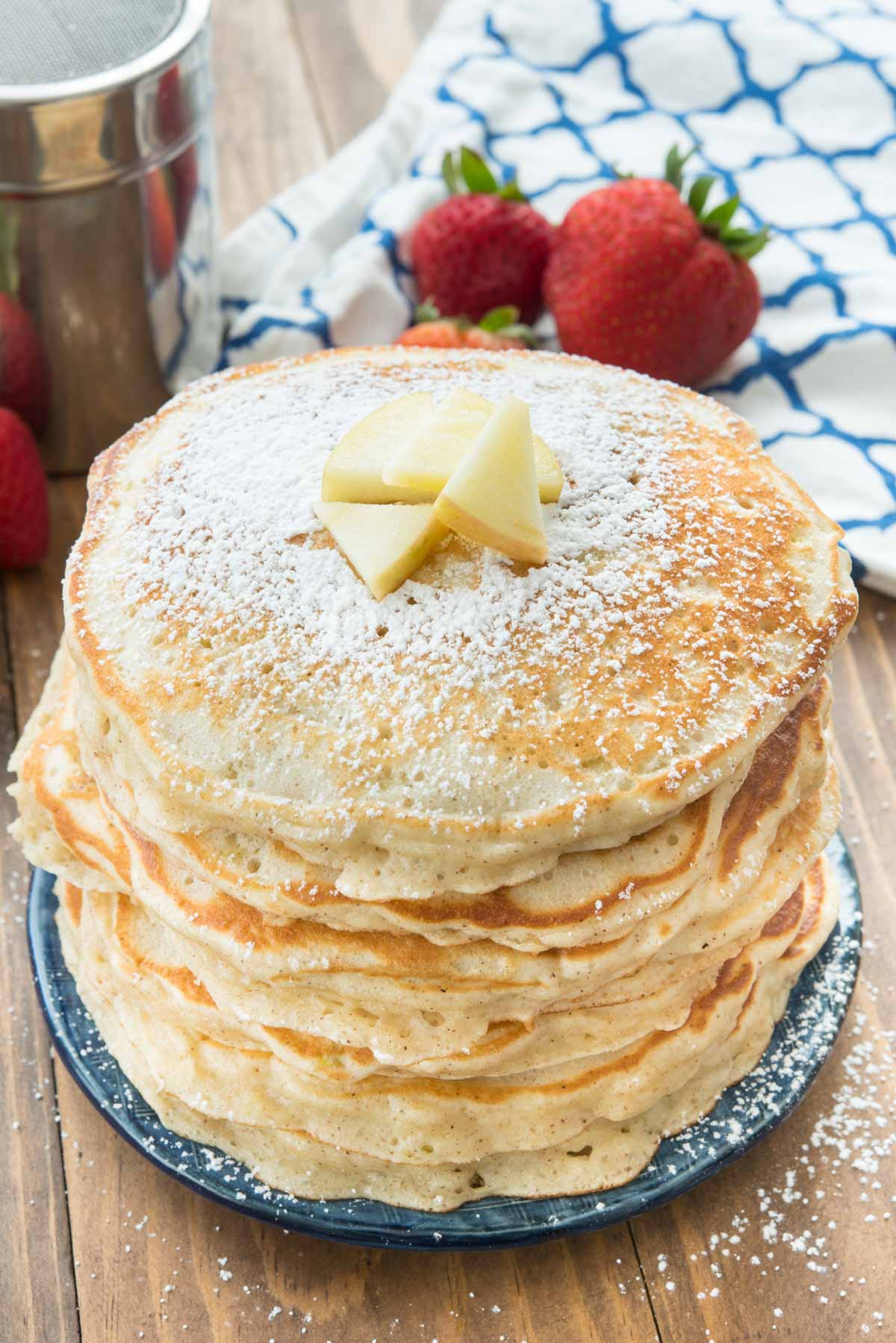 stacked pancakes with apple slices on top.