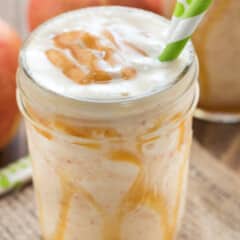 smoothie in a mason jar with caramel and two green straws in the drink.