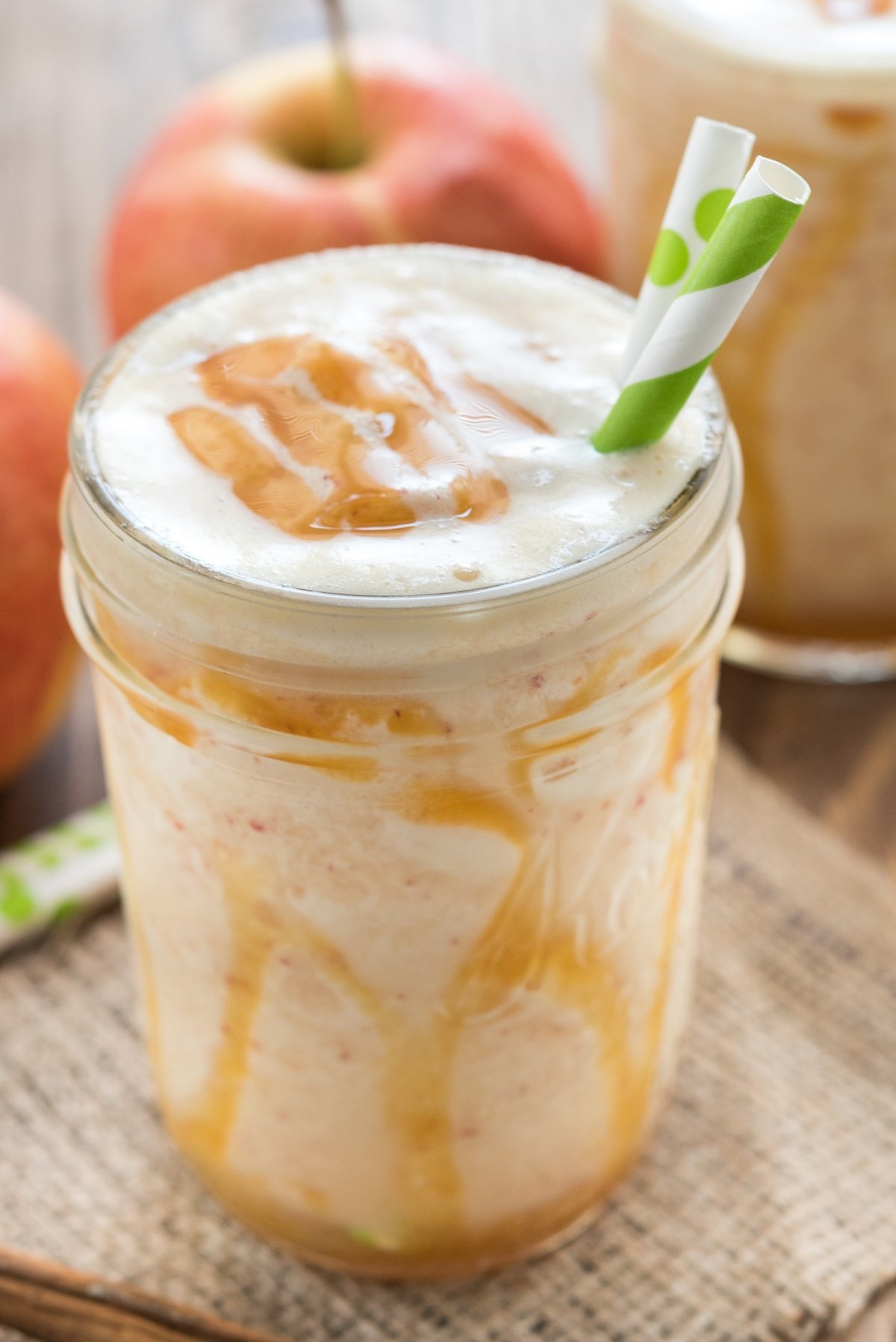 smoothie in a mason jar with caramel and two green straws in the drink.