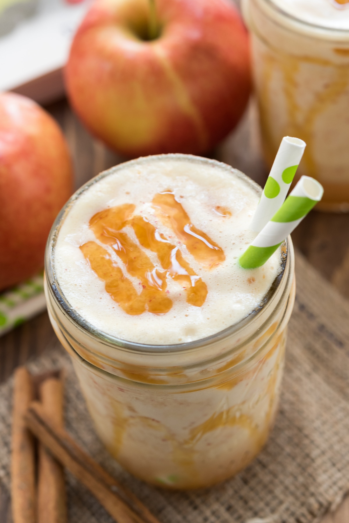 smoothie in a mason jar with caramel and two green straws in the drink.