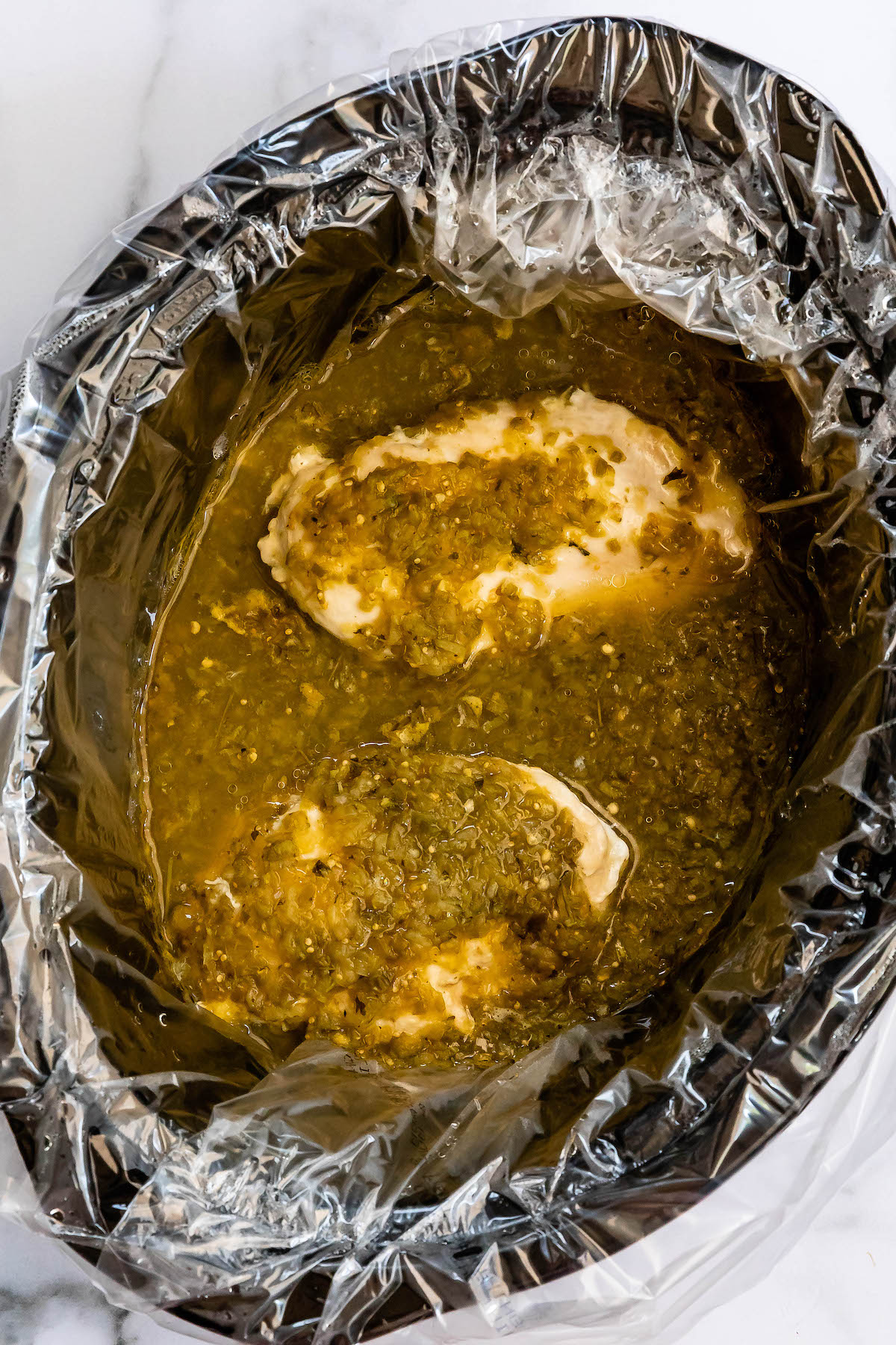 2 chicken breasts in crockpot with green salsa.