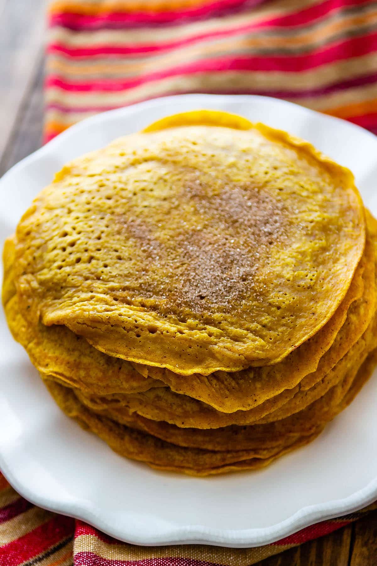 pumpkin pancakes stacked up on a white plate.