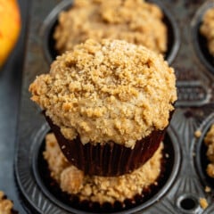 apple muffins in a brown cupcake tin with a crumble topping.