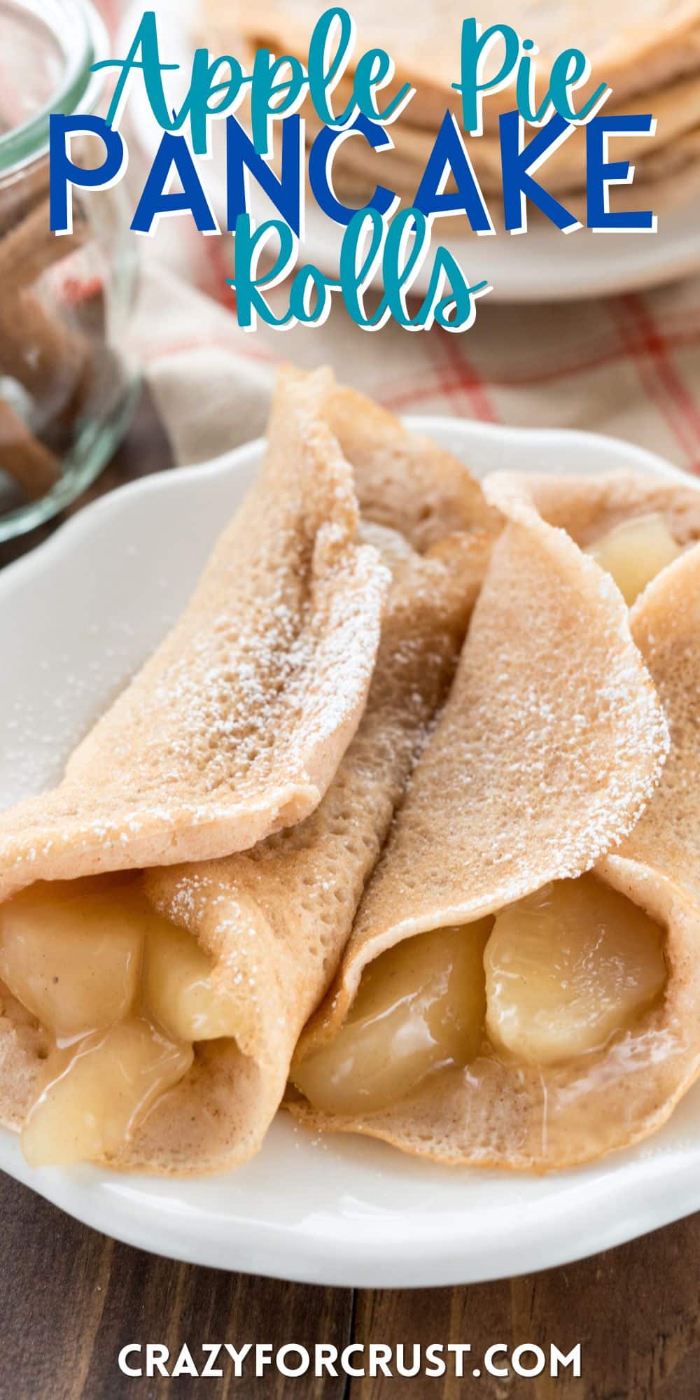 apples rolled up in pancakes on a white plate with powdered sugar on top with words on the image.