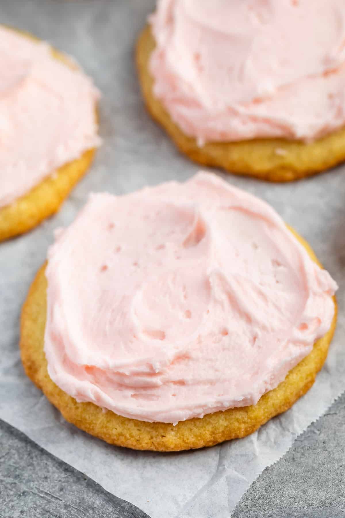 stacked yellow sugar cookies with pink frosting on top.