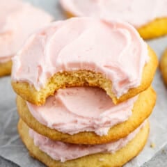 stacked yellow sugar cookies with pink frosting on top.