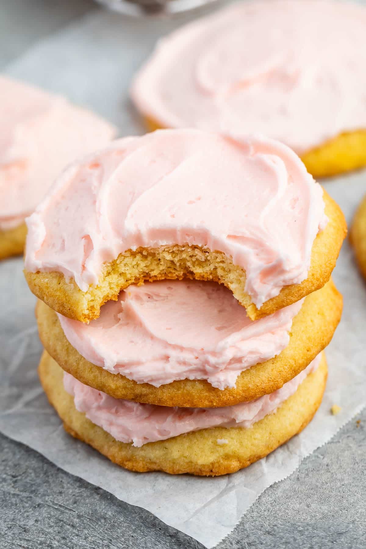 stacked yellow sugar cookies with pink frosting on top.