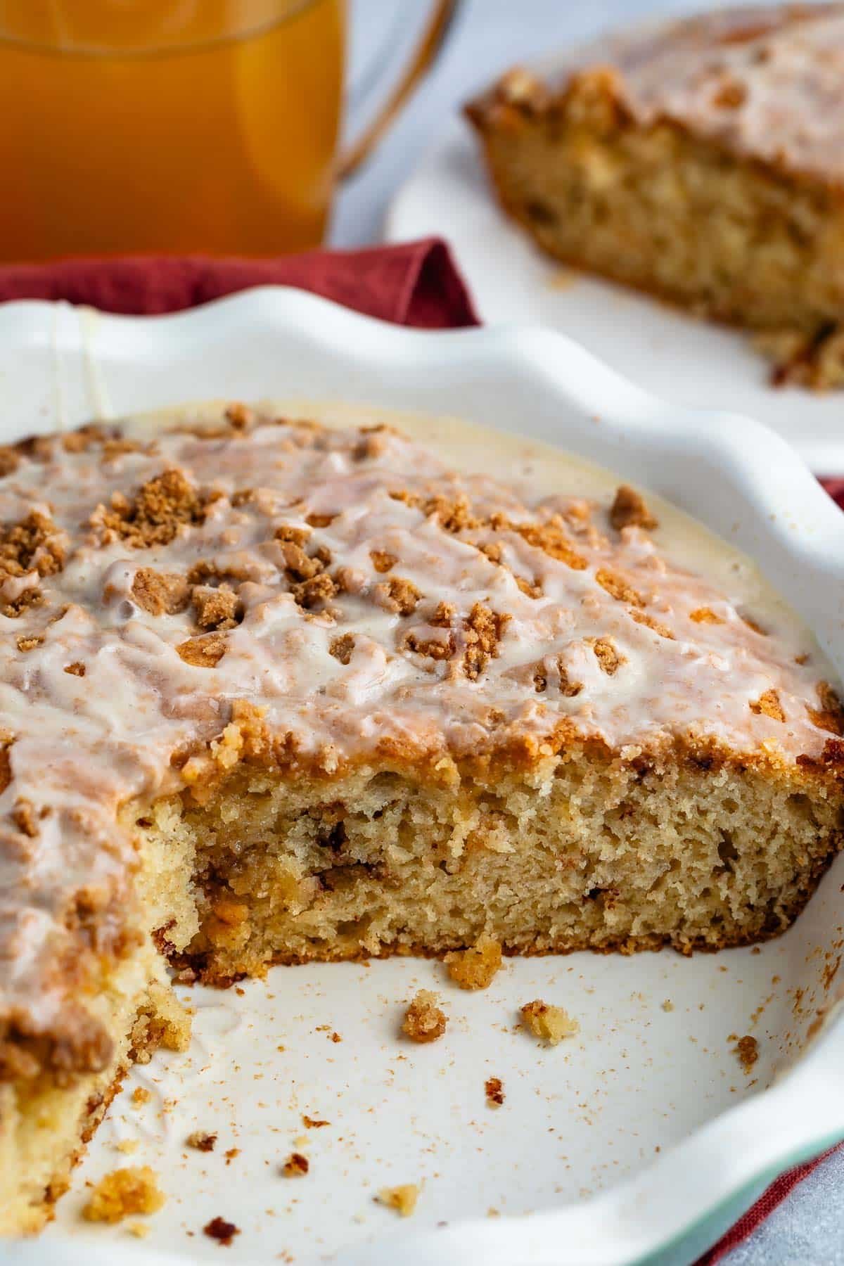 apple fritter coffee cake in a white pan with glaze on top.
