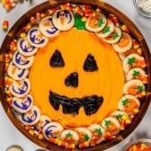 frosting board with pumpkin decorations and pumpkin cookies around it.