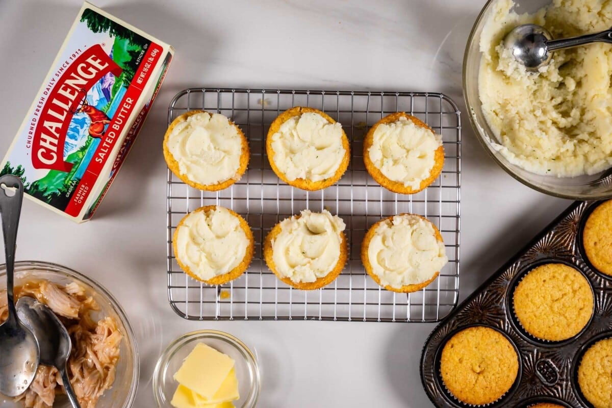 6 cupcakes on a rack frosted with mashed potatoes and butter box and ingredients around.