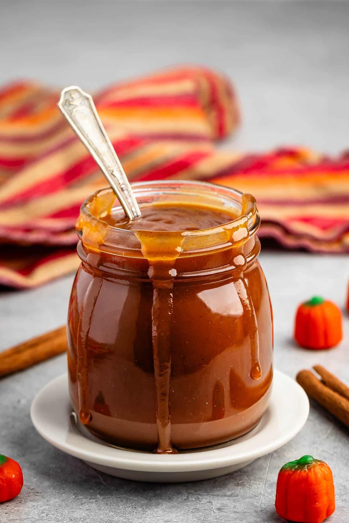 caramel in a clear jar with a spoon scooping it.