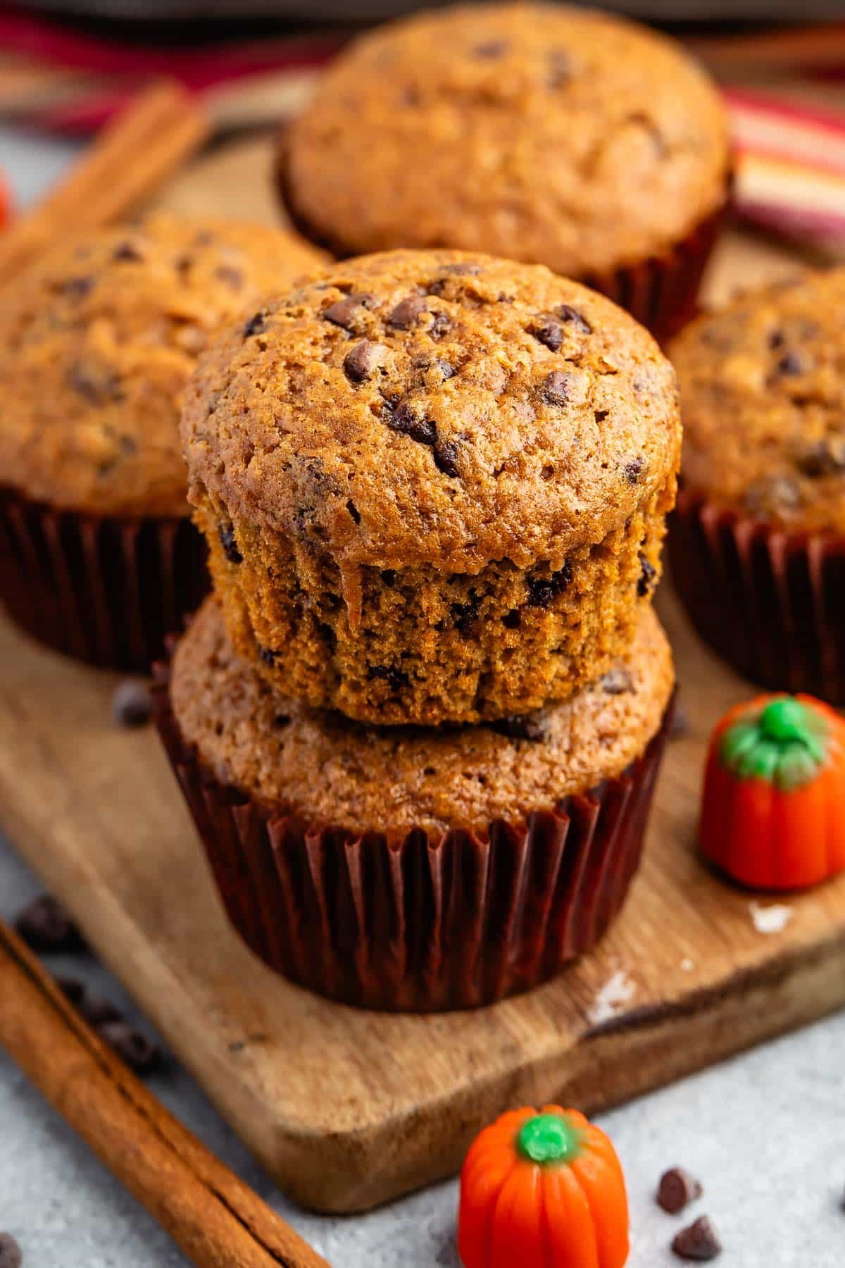 stacked muffins on a brown cutting board.