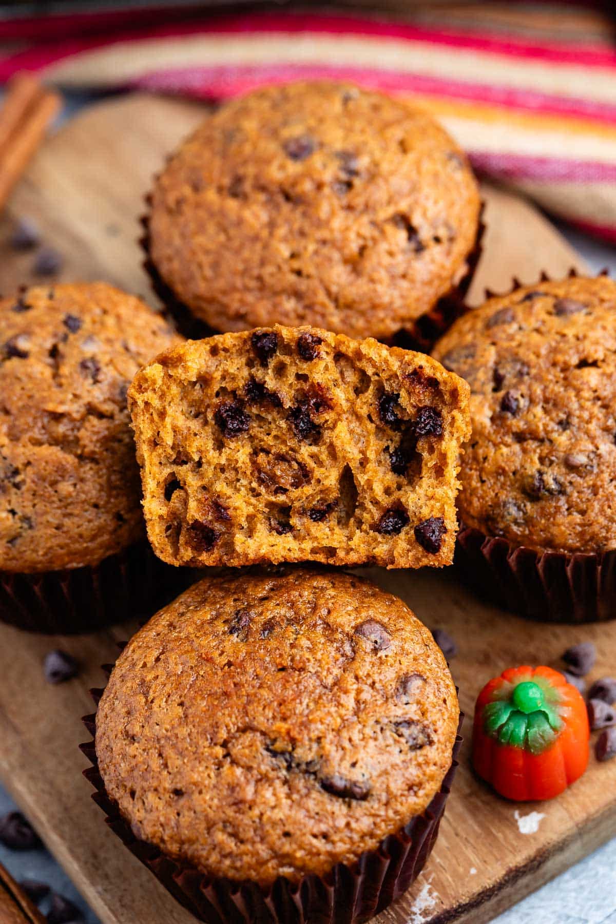 stacked muffins on a brown cutting board.