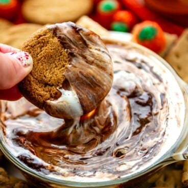 hand holding cookie that's being dipped into a white and brown dip.