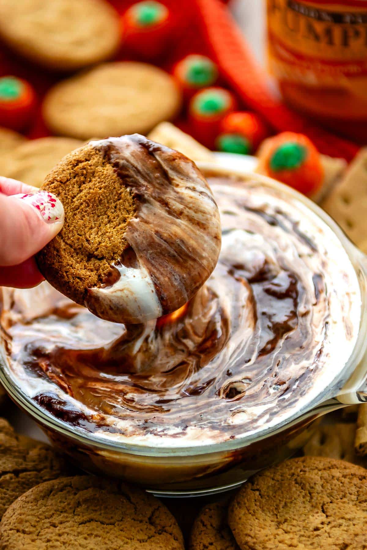 hand holding cookie that's being dipped into a white and brown dip.