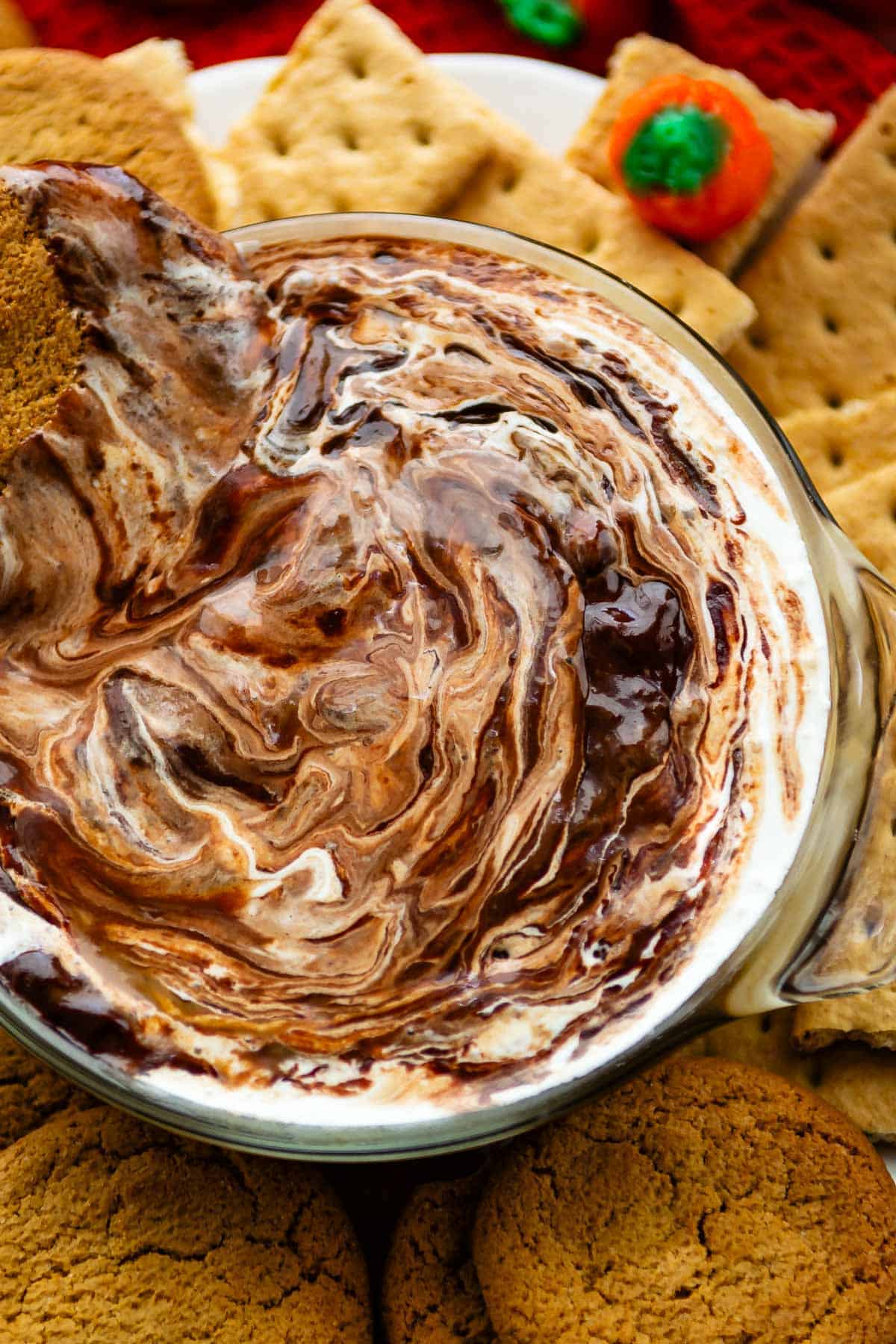 hand holding cookie that's being dipped into a white and brown dip.