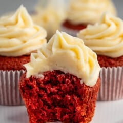 red cupcakes with frosting on top on a white plate.