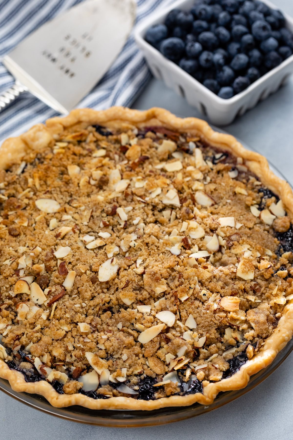blueberry pie in a clear plate with crumble on top.