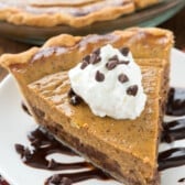 chocolate chip pie on a white plate with chocolate drizzled under.