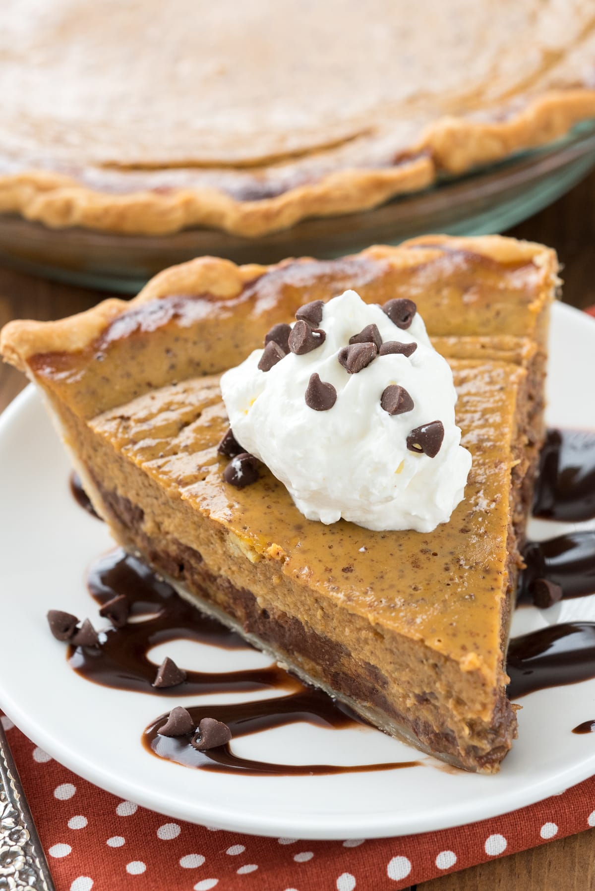 chocolate chip pie on a white plate with chocolate drizzled under.