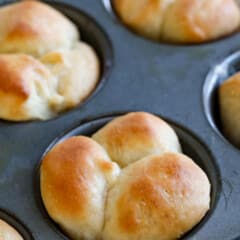 multiple dinner rolls in a stainless steal muffin tin.