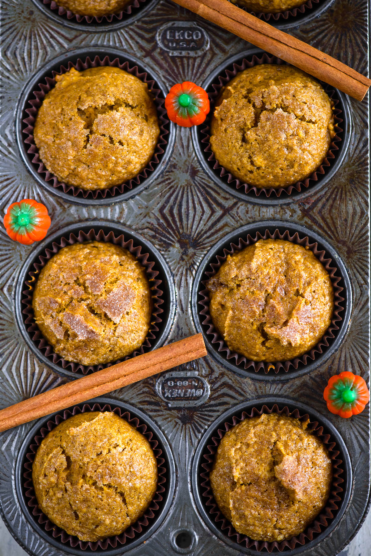 pumpkin muffins stacked in brown cupcake wrappers in a baking tin.