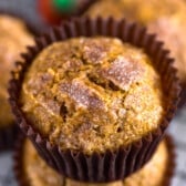 pumpkin muffins stacked in brown cupcake wrappers.