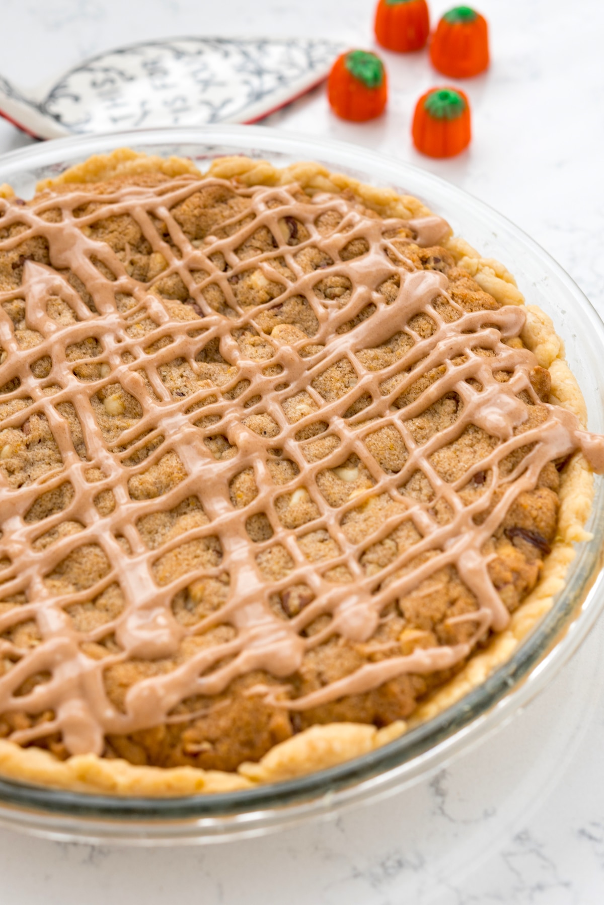 cookie pie in a clear pie pan with glaze drizzled over.