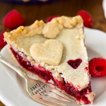 one slice of pie with raspberry filling and a heart sliced out of the dough.