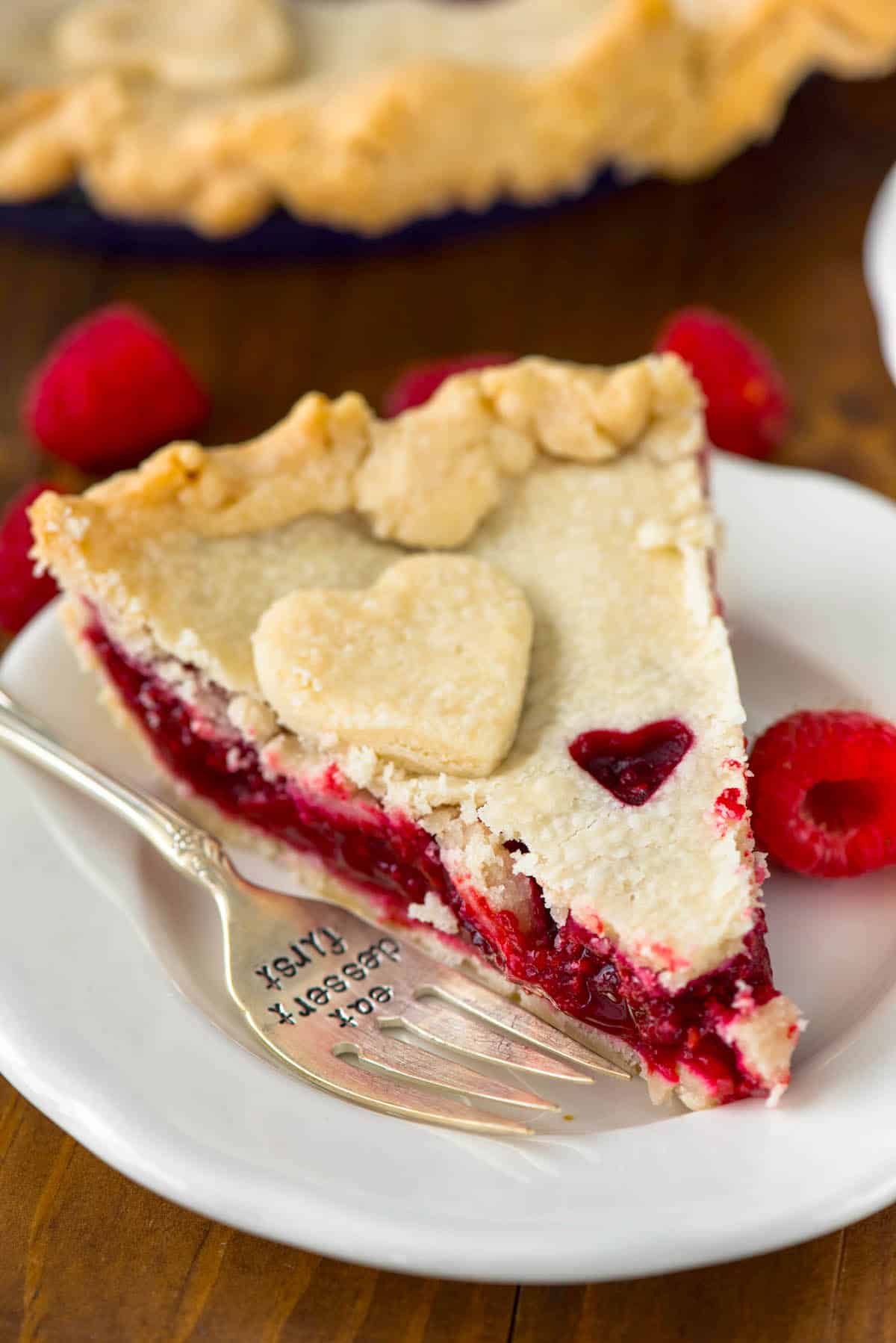 one slice of pie with raspberry filling and a heart sliced out of the dough.