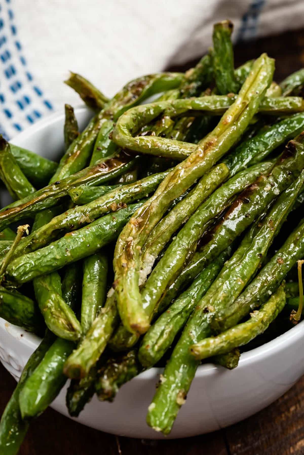 greens beans piled on each other in a white bowl.