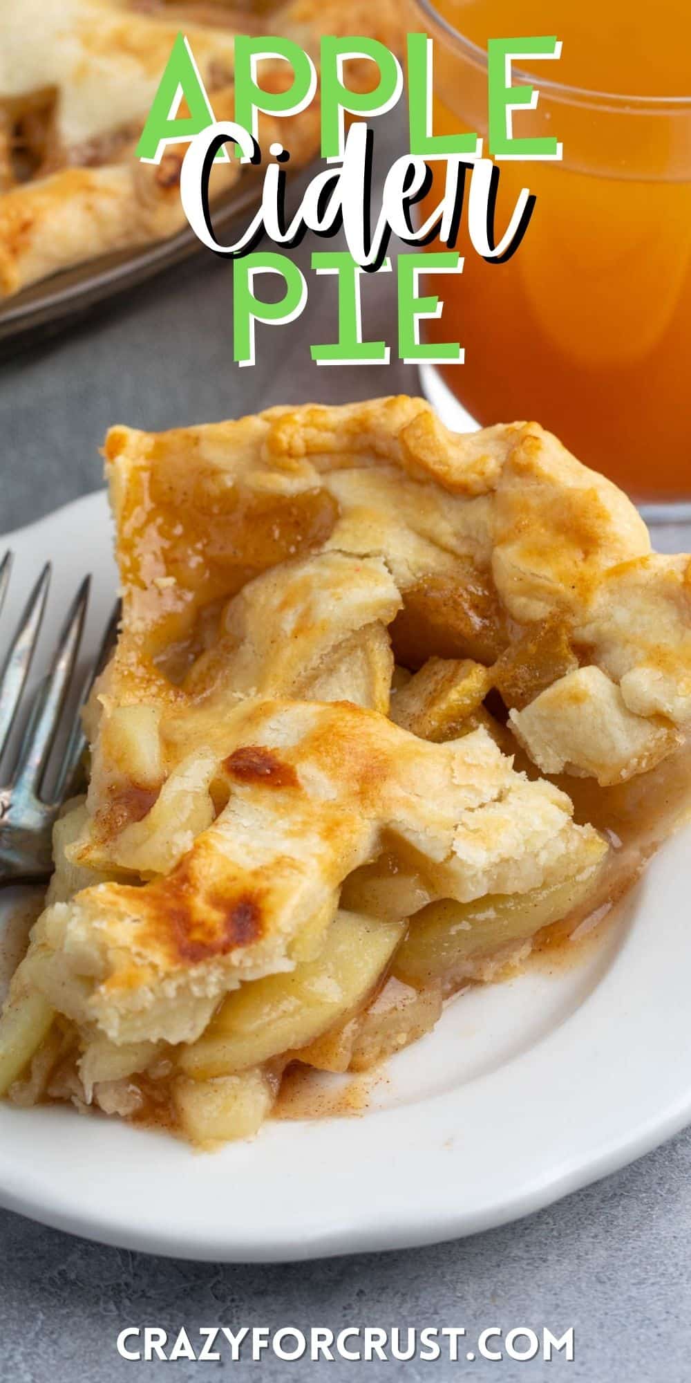 apple pie on a white plate next to a fork and a glass of apple cider with words on the image.